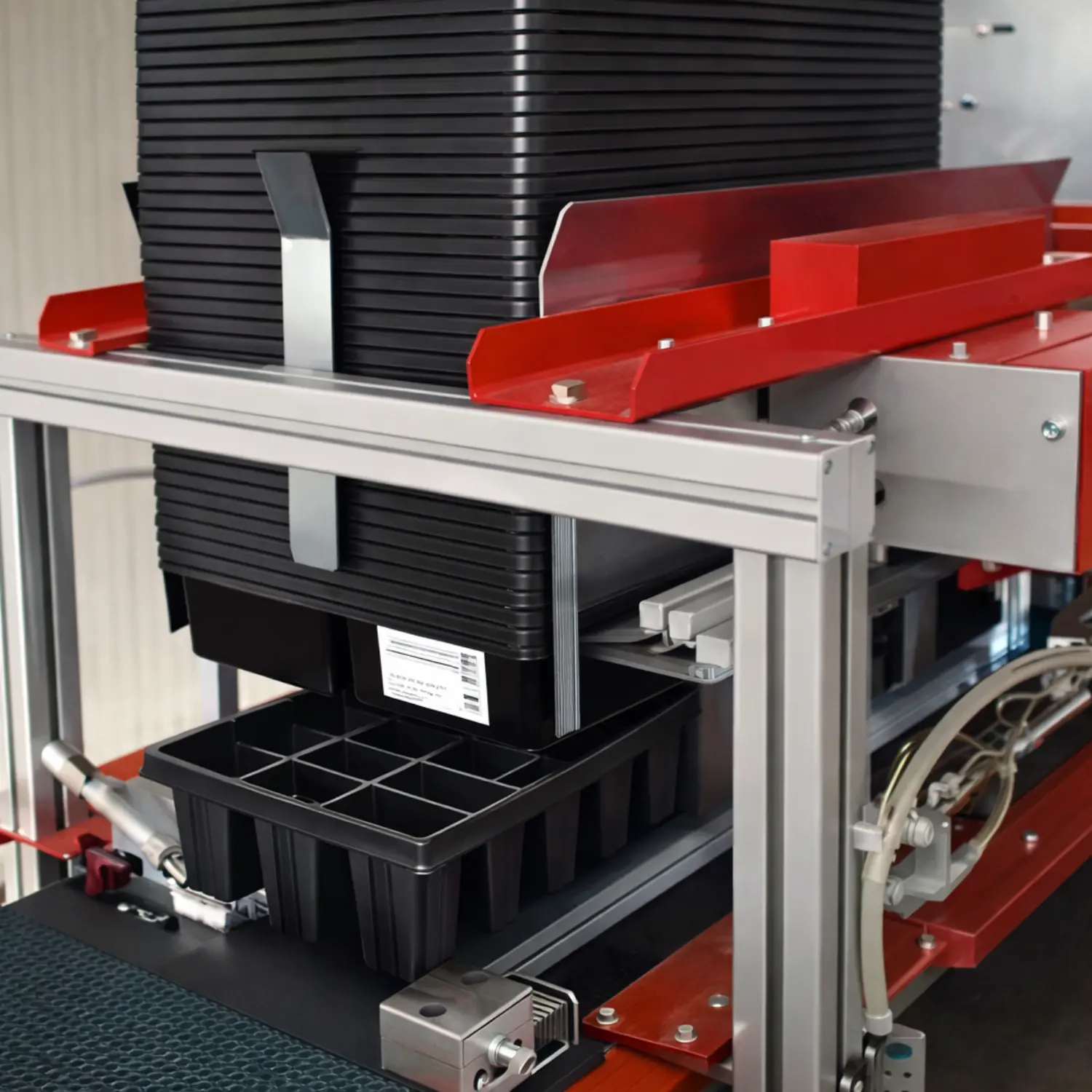 Close-up view of a tray destacker with a stacked pile of plant trays positioned inside the machine.